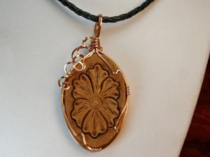 Carved leather pendant with wire wrapped bezel.