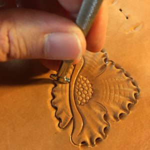 Hand tooling a flower in leather.