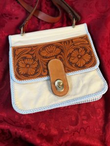 A soft leather handbag with a carved front flap.